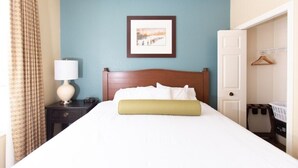 A hotel room with a bed, a nightstand with a lamp, a framed picture on the wall, and a door leading to a closet. - 1 Bedroom Villa at Mountain Run at Boyne Mountain (Boyne Falls)