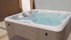 A hot tub with a step for access, a control panel, and a water level indicator.