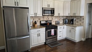 A modern kitchen with white cabinetry, stainless steel appliances, and a granite countertop.