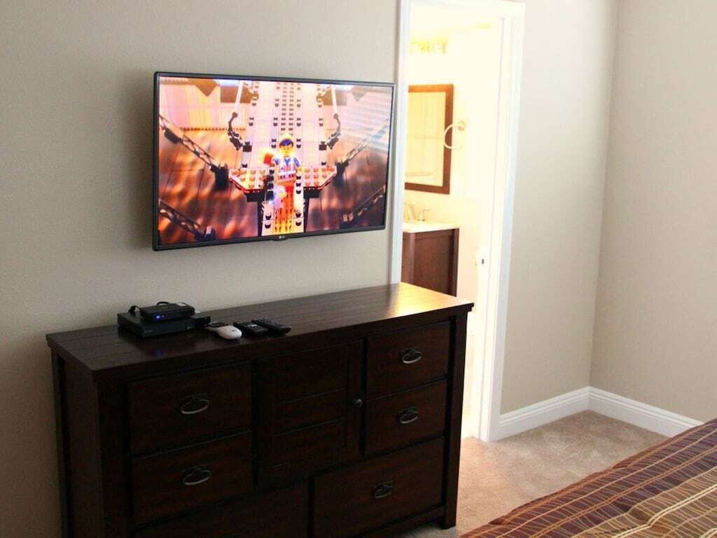 Ein Zimmer mit einem Flachbildfernseher, der an der Wand über einer dunklen Holzkommode angebracht ist.