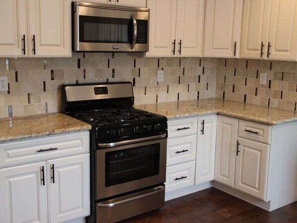A kitchen with white cabinets, a stainless steel microwave, a gas stove, and a built-in oven.