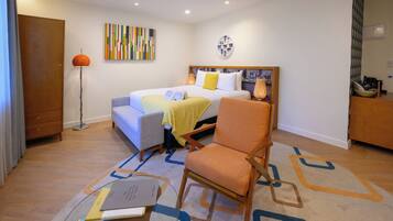 A hotel room with a bed, a chair, a desk, and a floor lamp.