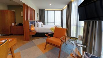 A hotel room with a bed, a desk, a chair, a TV, and a window with curtains.