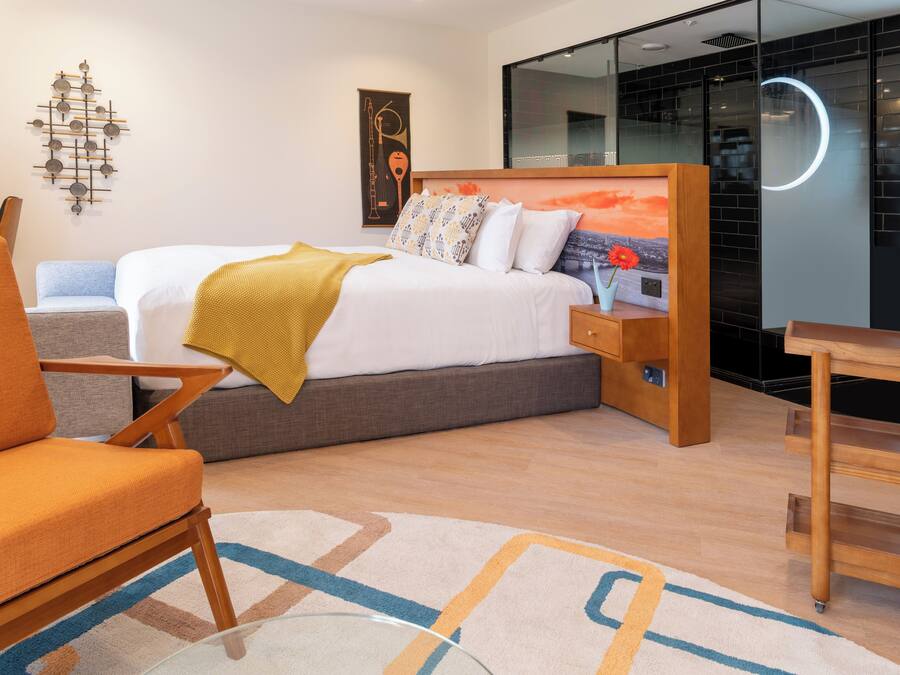 Una habitació d'hotel moderna amb un llit, una taula de treball i una cadira.