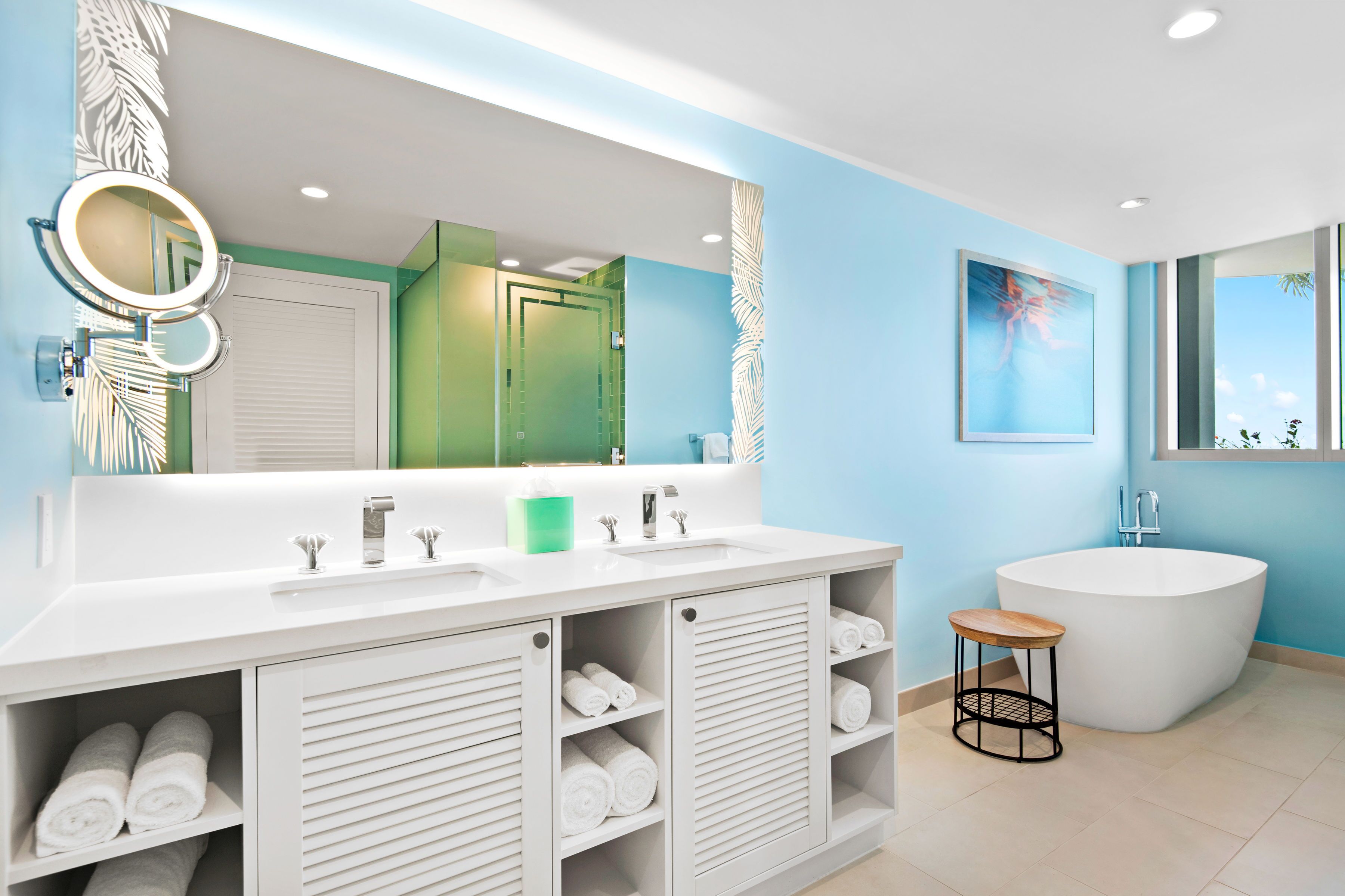 A modern bathroom with a large vanity, a freestanding bathtub, and a small stool.