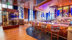A bar area with wooden flooring, bar stools, and a display of liquor bottles.