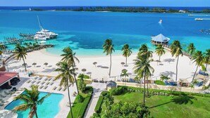 Un complexe hôtelier doté d’une piscine, d’une plage et d’un quai avec un bateau.