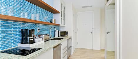 A modern kitchen with blue-tiled backsplash, stainless steel appliances, and wooden shelves.
