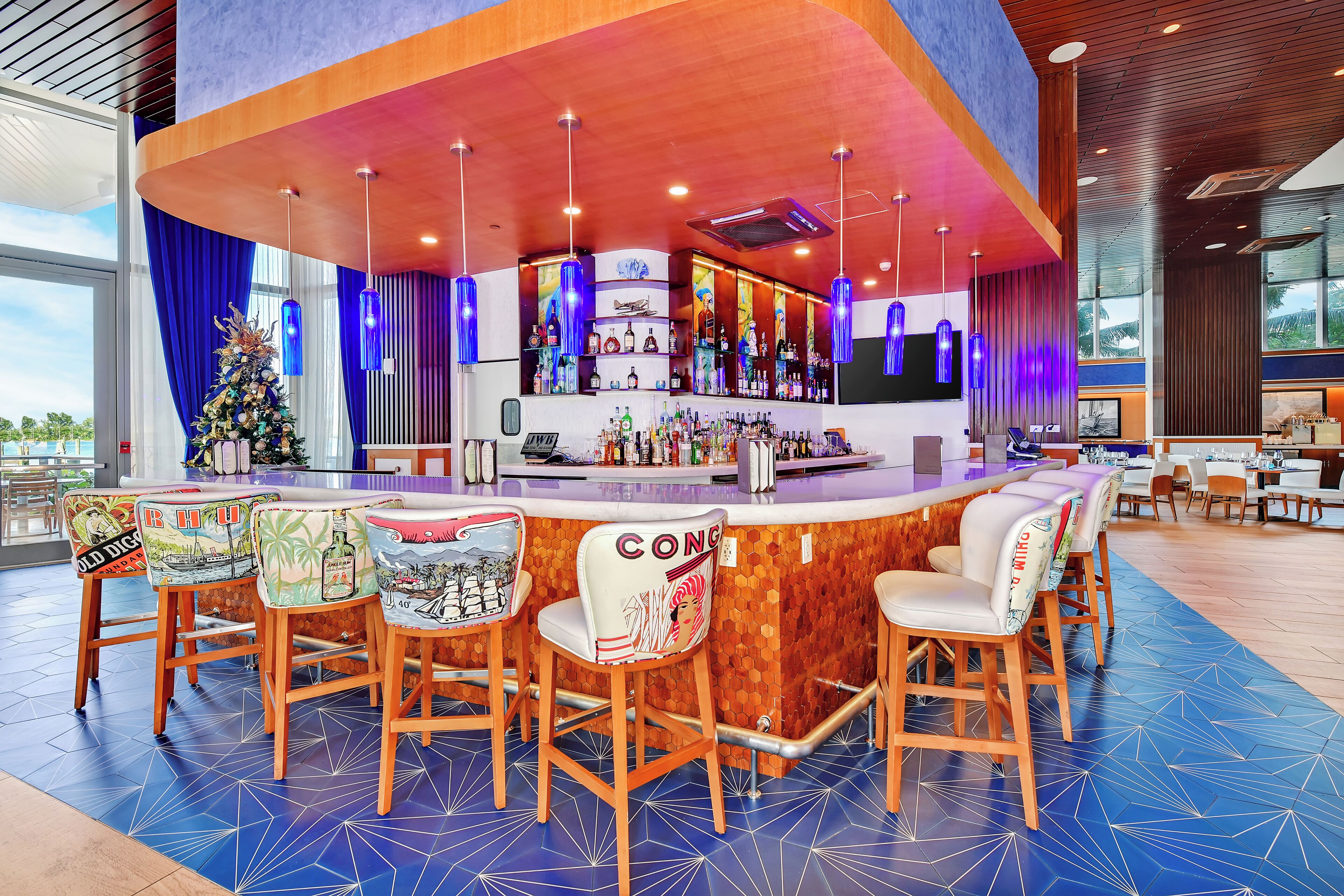 A bar area with a wooden counter, bar stools, and a Christmas tree.