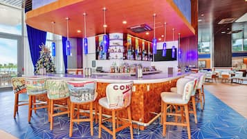 A bar area with a wooden counter, bar stools, and a Christmas tree.