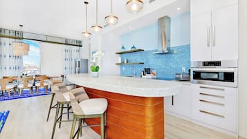 Una cocina moderna con una isla central, electrodomésticos de acero inoxidable y un respuesto de azulejos azules.