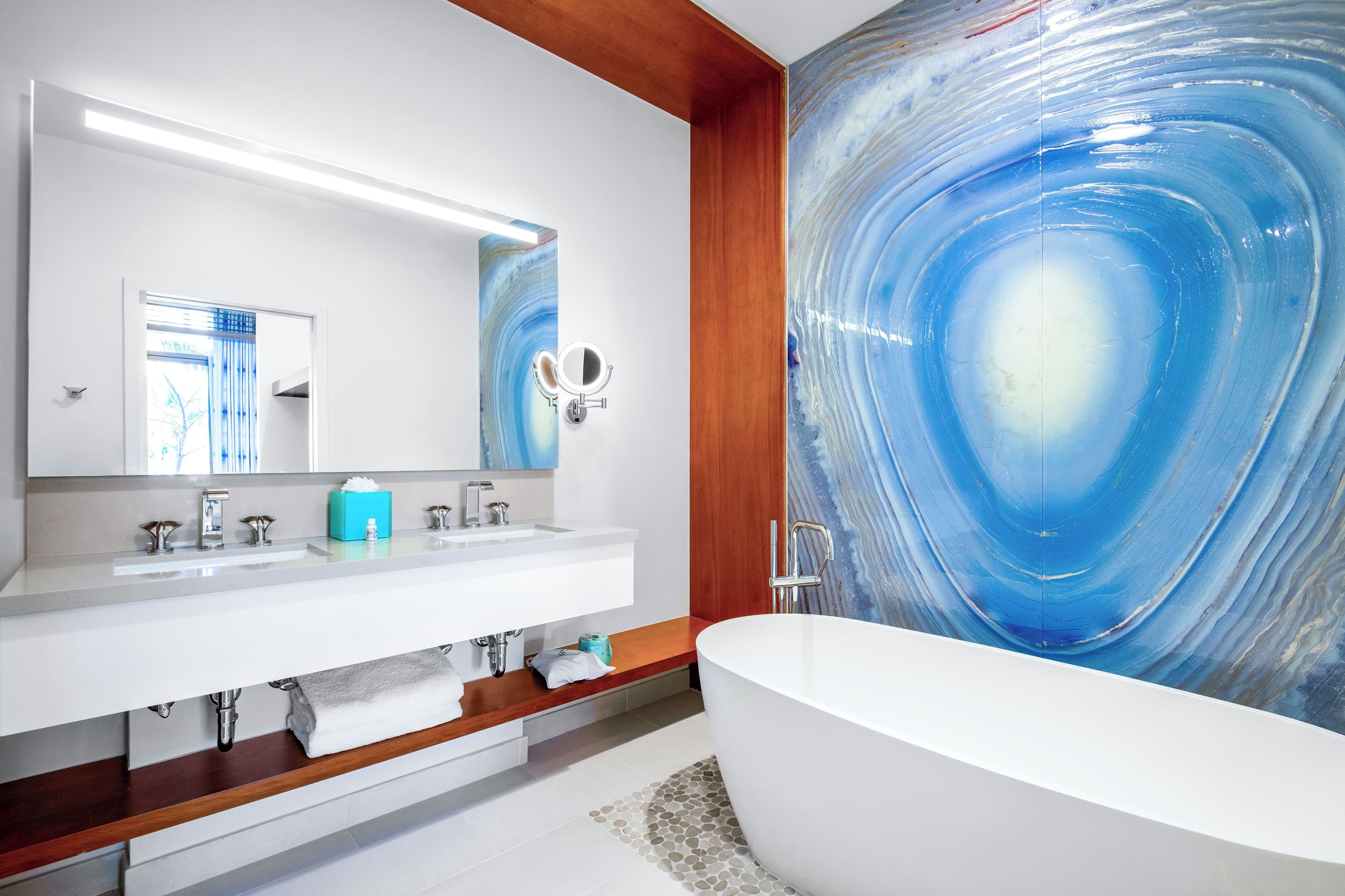 Une salle de bain moderne avec une baignoire sur pieds, un grand miroir et un mur en marbre.