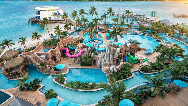 A resort with multiple swimming pools, palm trees, and a beach area.