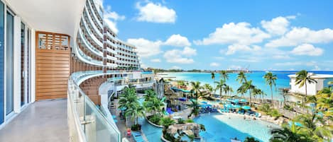 A hotel balcony with a view of a resort pool area, including a water slide and lounge chairs.