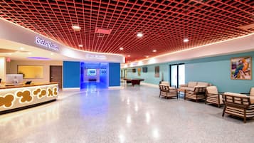 A spacious lobby with a pool table, seating area, and a movie theater entrance.