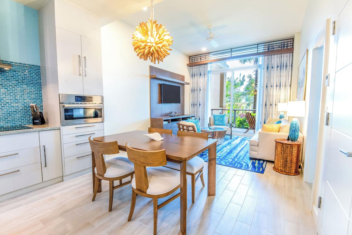 Eine moderne Küche mit Essbereich, einem Fernseher und einem Balkon mit Blick auf Grünflächen.