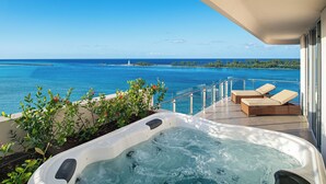 Un balcon doté d’un jacuzzi, de chaises longues et offrant une vue sur l’océan et un phare.