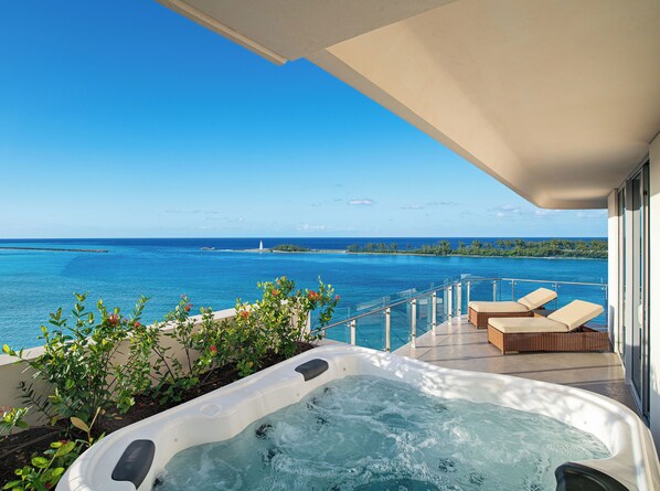 Un balcon doté d’un jacuzzi, de chaises longues et offrant une vue sur l’océan et un phare.