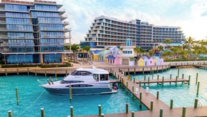 A marina with a yacht docked, wooden walkways, and modern buildings in the background.