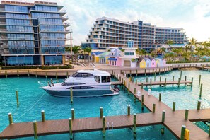A marina with a yacht docked, wooden walkways, and modern buildings in the background.
