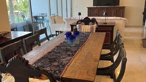 Een eethoek met een lange houten tafel, donkerhouten stoelen met beklede zitplaatsen en een gedessineerd tapijt.