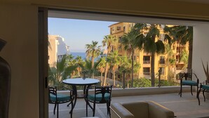 Een balkon met een tafel en stoelen, met uitzicht op een gebied met palmbomen en een gebouw met balkons.