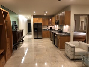 A modern kitchen with wooden cabinets, stainless steel appliances, and a marble floor.