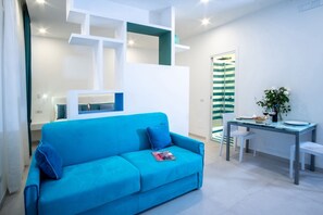 Een moderne woonkamer met een blauwe bank, witte planken en een gestreept douchegordijn.