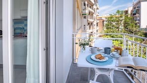 Un balcon avec une table préparée pour le petit-déjeuner, donnant sur un quartier résidentiel composé de plusieurs immeubles.