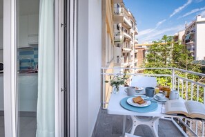 A balcony with a table set for breakfast, overlooking a residential area with multiple buildings.