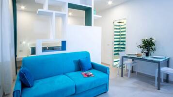 Un salon moderne avec un canapé bleu, des étagères blanches et un rideau de douche à rayures.