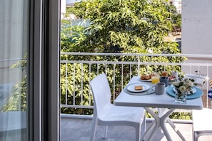 Un balcón con una mesa preparada para el desayuno, incluyendo croissants, muffins y jugo de naranja.