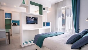 Une chambre moderne équipée d’un lit, d’une télévision, d’un bureau et d’une kitchenette.