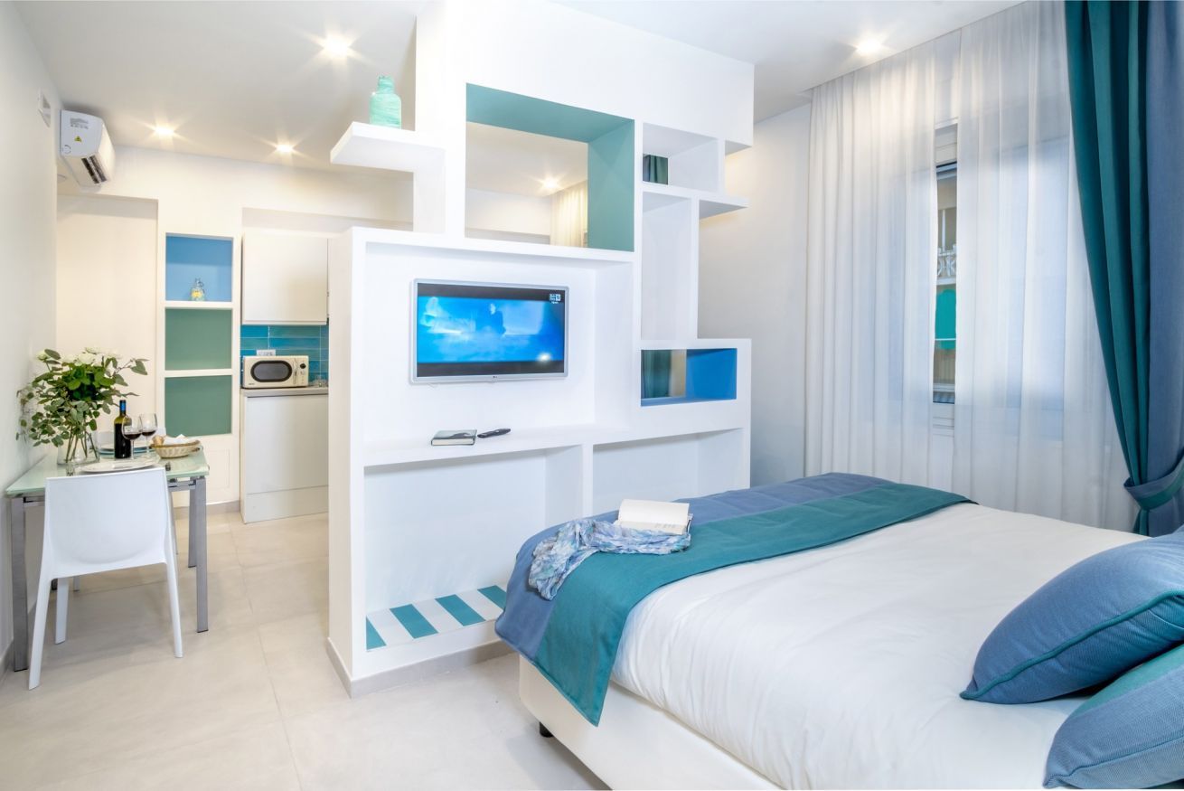 Une chambre moderne équipée d’un lit, d’une télévision, d’un bureau et d’une kitchenette.