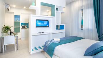 Une chambre moderne équipée d’un lit, d’une télévision, d’un bureau et d’une kitchenette.