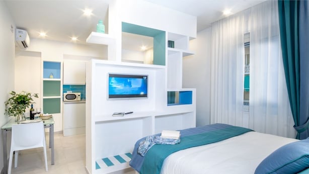 Une chambre moderne équipée d’un lit, d’une télévision, d’un bureau et d’une kitchenette.