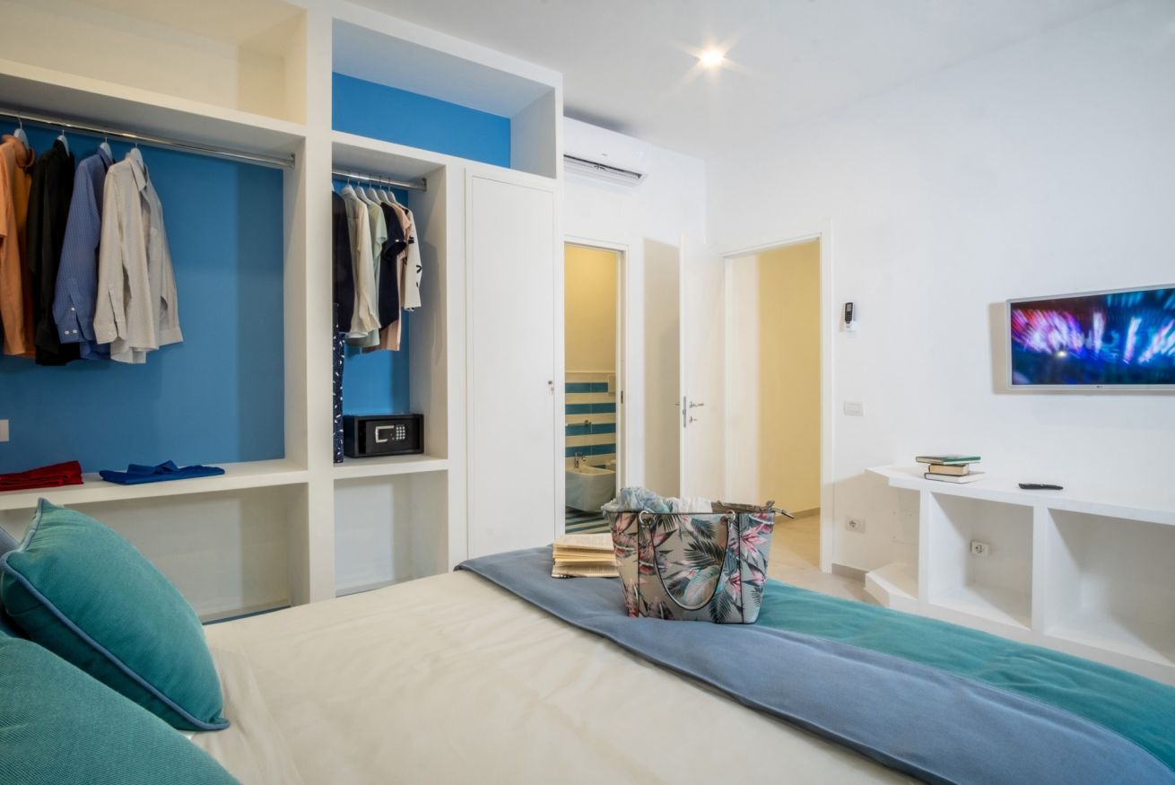 Ein Schlafzimmer mit Bett, Kleiderschrank, Fernseher und Schreibtisch.