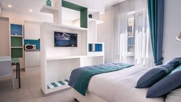 Une chambre moderne équipée d’un lit, d’une télévision, d’un bureau et d’une kitchenette.