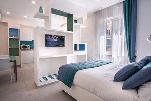Une chambre moderne équipée d’un lit, d’une télévision, d’un bureau et d’une kitchenette.