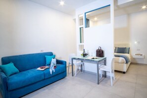 A modern living room with a blue sofa, a glass-top table, and a white chair.