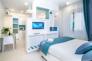 Un dormitorio moderno con cama, televisor y zona de escritorio.