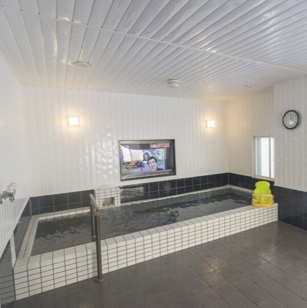 Une salle de spa équipée d’une baignoire, d’un téléviseur et d’une horloge murale.