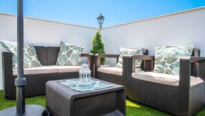 Un espace extérieur aménagé avec des meubles en osier, des coussins et une lanterne.