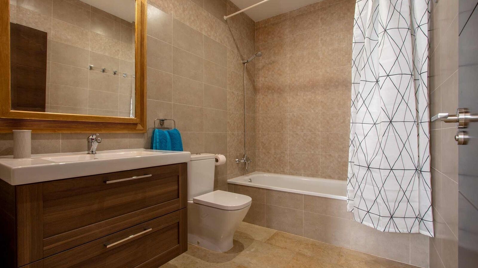 A bathroom with a wooden vanity, a toilet, a bathtub, and a shower.