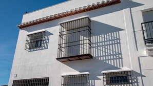 Un bâtiment aux murs extérieurs blancs, doté d’un toit en tuiles et de fenêtres grillagées.