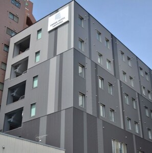 Un immeuble abritant un hôtel à plusieurs étages, sur lequel on peut lire l’inscription « FRAME HOTEL SAPPORO ».