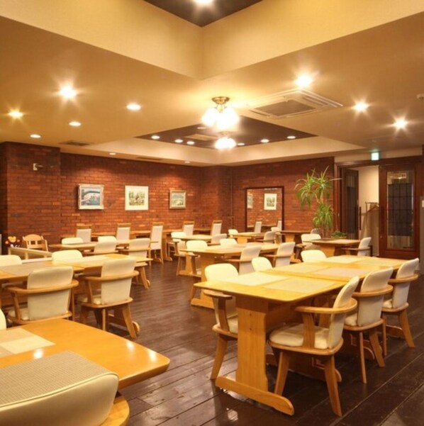 A conference room with wooden tables and chairs, brick walls, and ceiling lights.