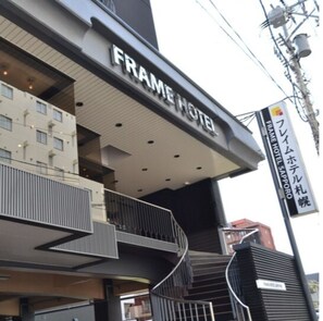 Un immeuble à plusieurs étages sur lequel on peut lire l’inscription « FRAME HOTEL ».