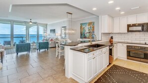 A modern kitchen with white cabinetry, a central island, and a view of the sea. - P5-0905 2B Tower 5 @ Portofino! (Pensacola Beach)