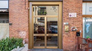 Un edificio de ladrillo con entrada por puerta de vidrio, un letrero de propiedad privada y un pequeño jardín con plantas.